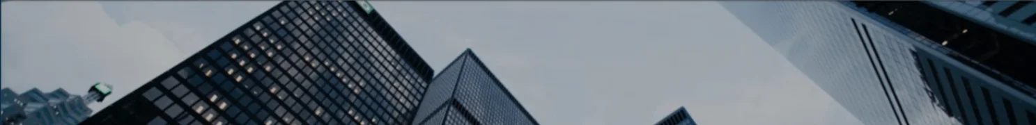 Angular view of illuminated glass office towers against a cloudy sky